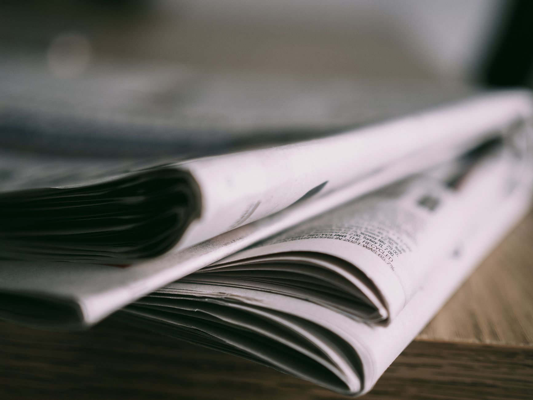 Stack of folded newspapers on a wooden table with a focus on printed pages. — Hellspin Online Casino: Quick Spin, Big Thrills