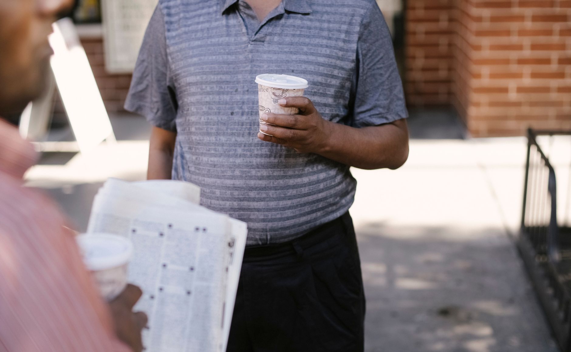 Crop anonymous ethnic male friends with coffee to go and newspaper speaking on city pavement — Wie gewinne ich im Jokery Casi