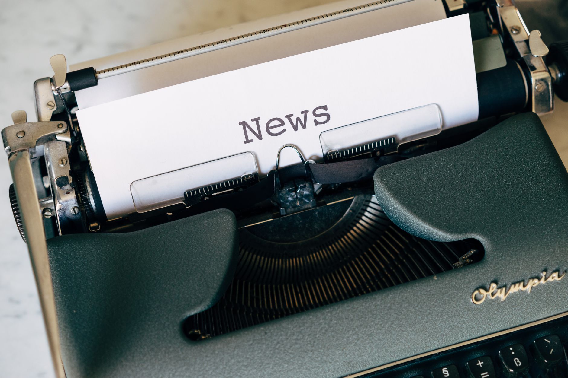 Close-up of a vintage Olympia typewriter with paper reading 'news'. Perfect for classic journalism themes. — Wie steht es um